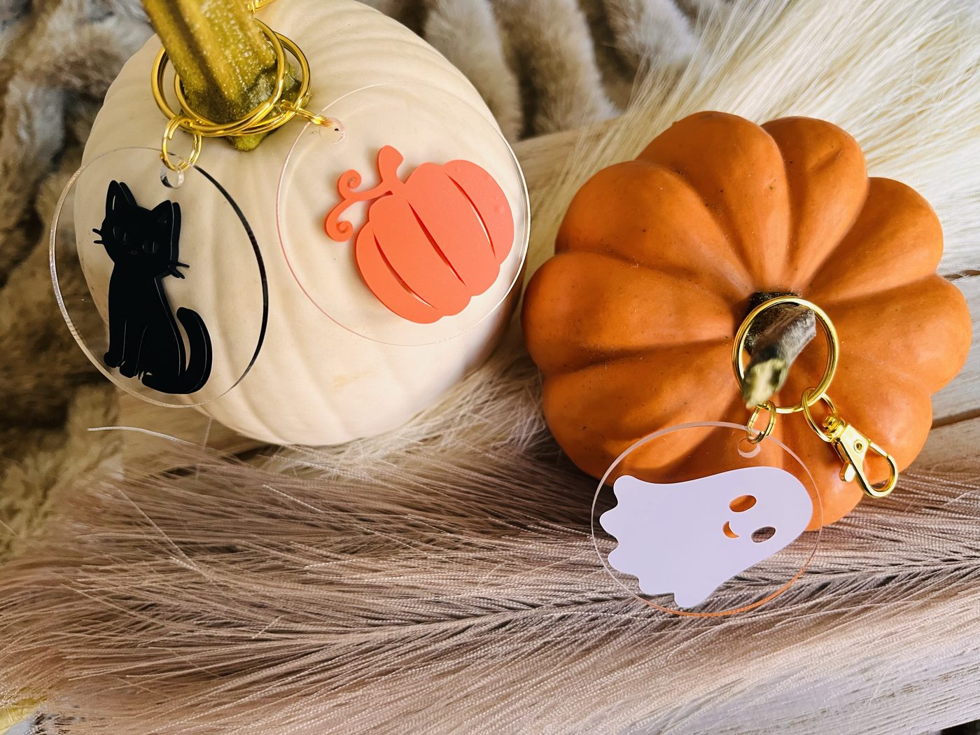 Black cat, pumpkin and ghost acrylic keychains with gold clasps on fall pumpkins